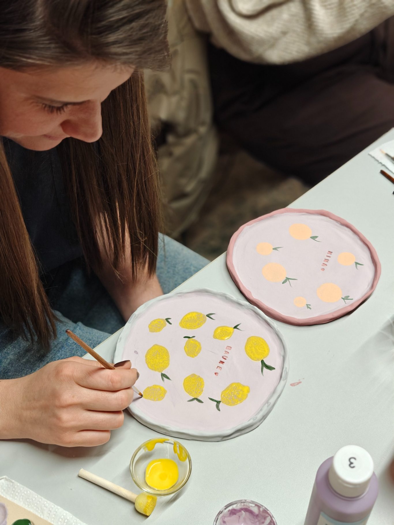 Een persoon schildt gele citroenen op een lila stoffen ondergrond.