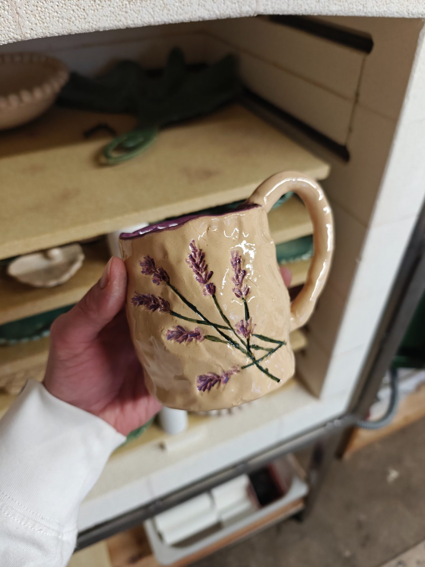 Aardewerken mok met paarse lavendelafbeeldingen en een handvat.