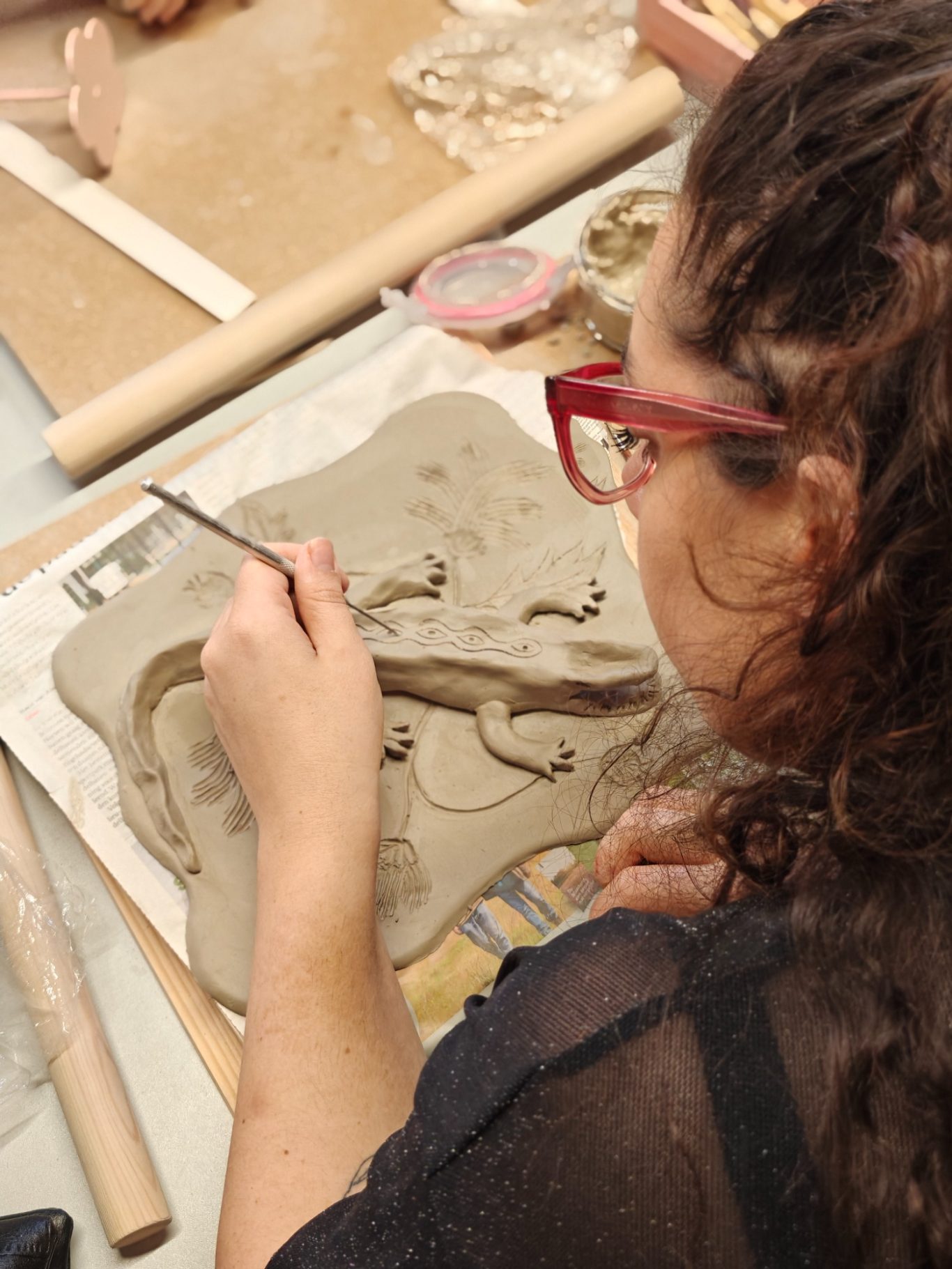 Vrouw in een creatief atelier die bezig is met het bewerken van klei.