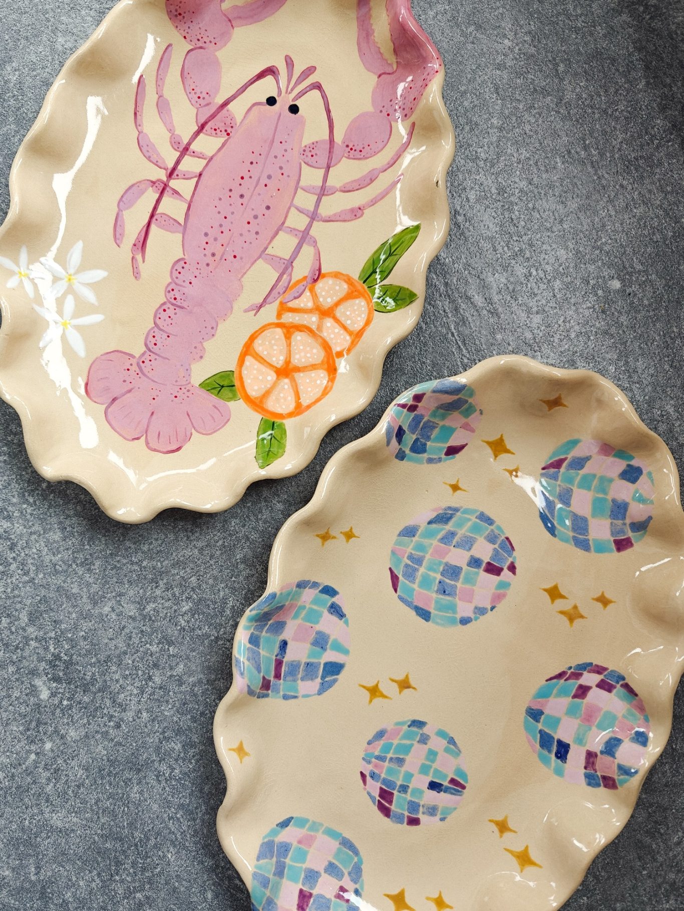 Twee keramische schalen met kleurrijke decoraties van een kreeft en abstracte patronen.